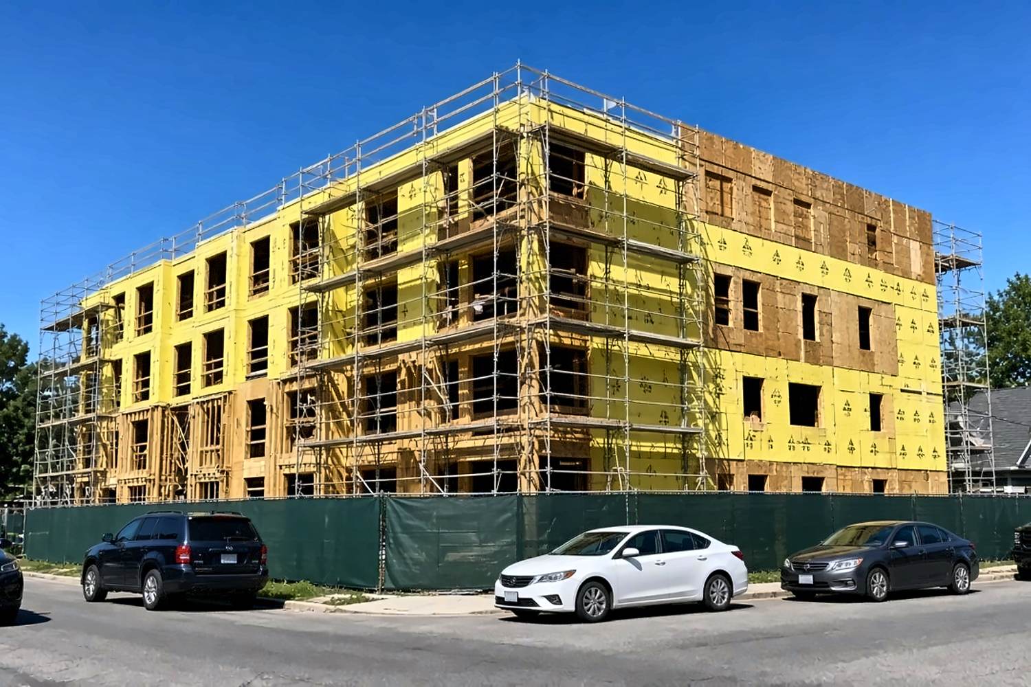 Urban mid-rise with yellow weather wrap and scaffolding