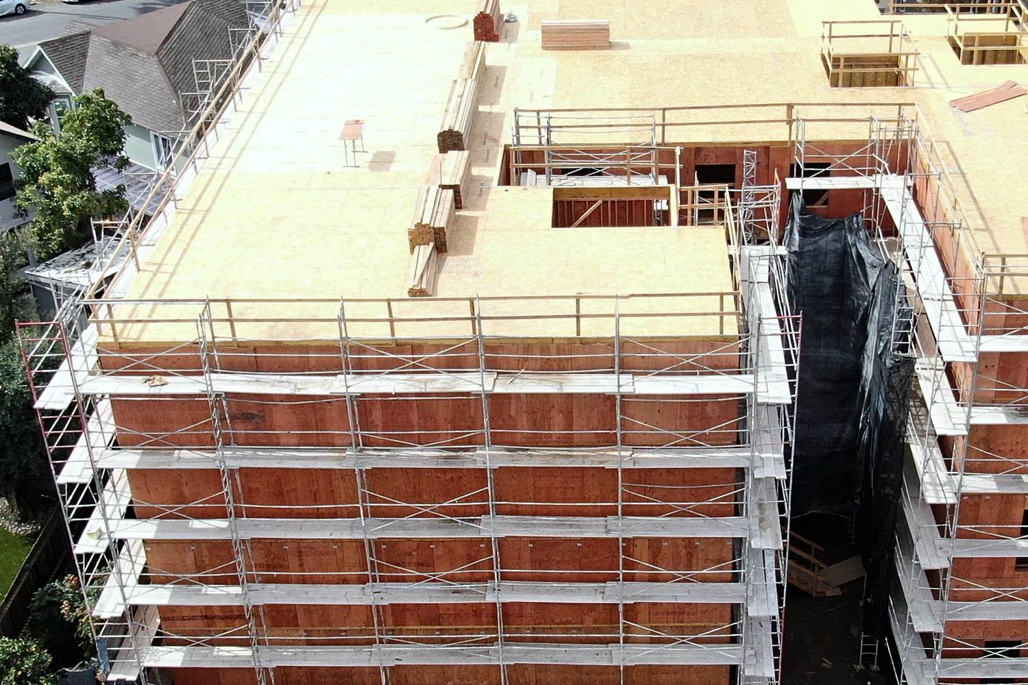 Aerial of multifamily building under scaffolding in neighborhood