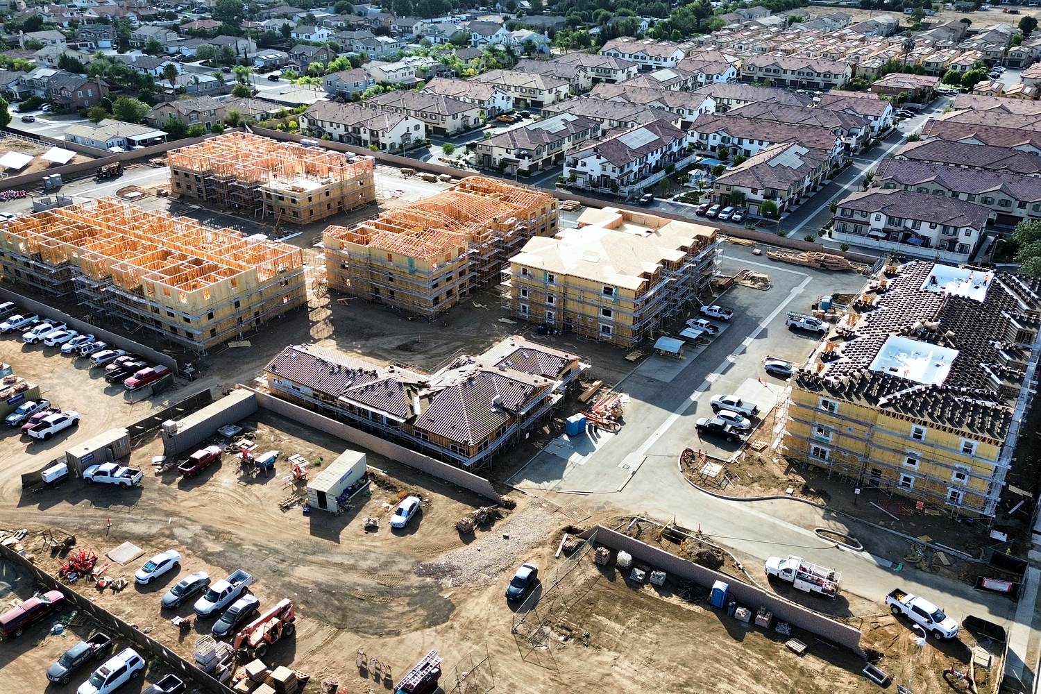 Aerial of multi-building framing and roof package with site trucks