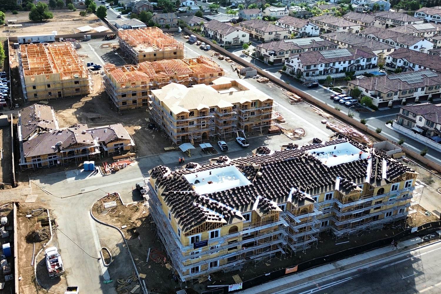 Aerial of multifamily wrap, windows, and roof tile staging with scaffolding